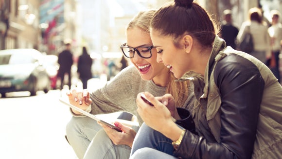 two-young-women-with-tablet-on-street