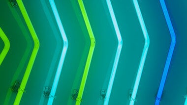 Row of neon arrows pointing right in shades of blue and green